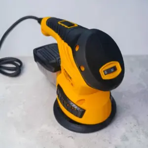 Lijadora eléctrica 3 en 1 rotoorbital amarilla y negra con control de velocidad, bolsa de polvo y cable, vista lateral sobre superficie gris.